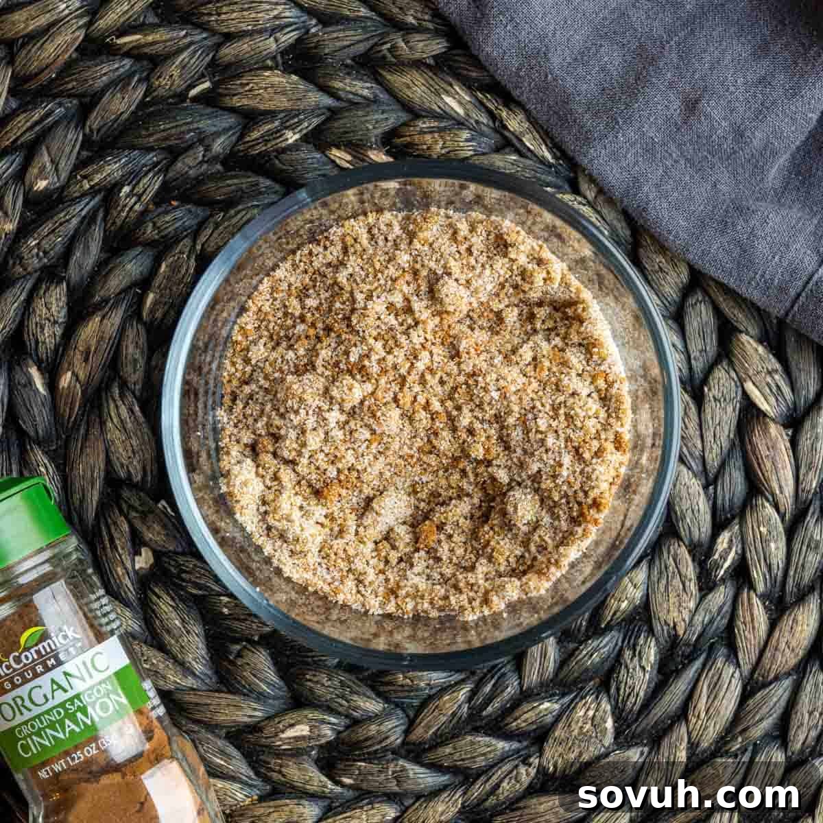 A bowl of granulated sugar with a cinnamon stick next to it, ready for apple pie filling.