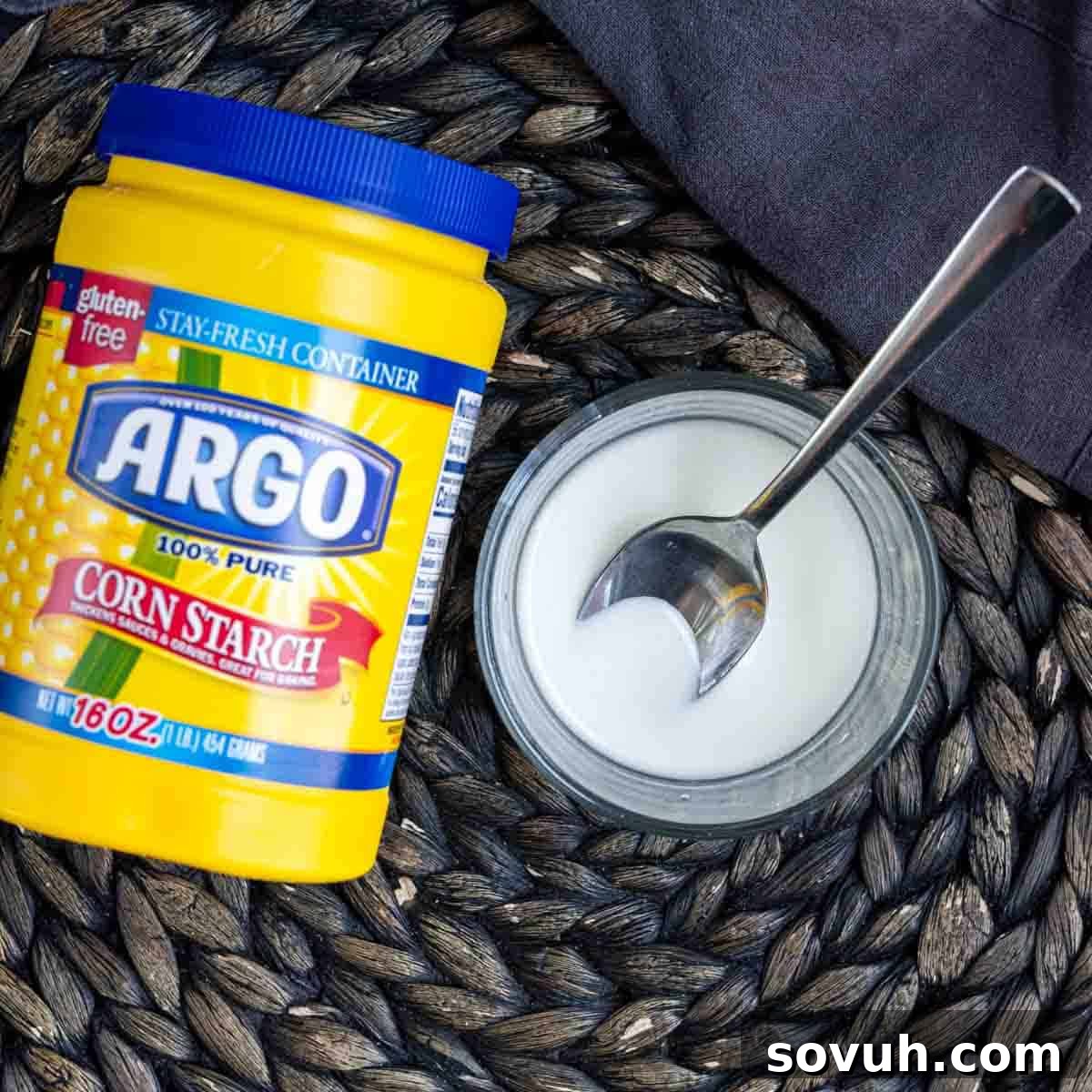 A jar of cornstarch next to a spoon, preparing to make the apple pie filling slurry.