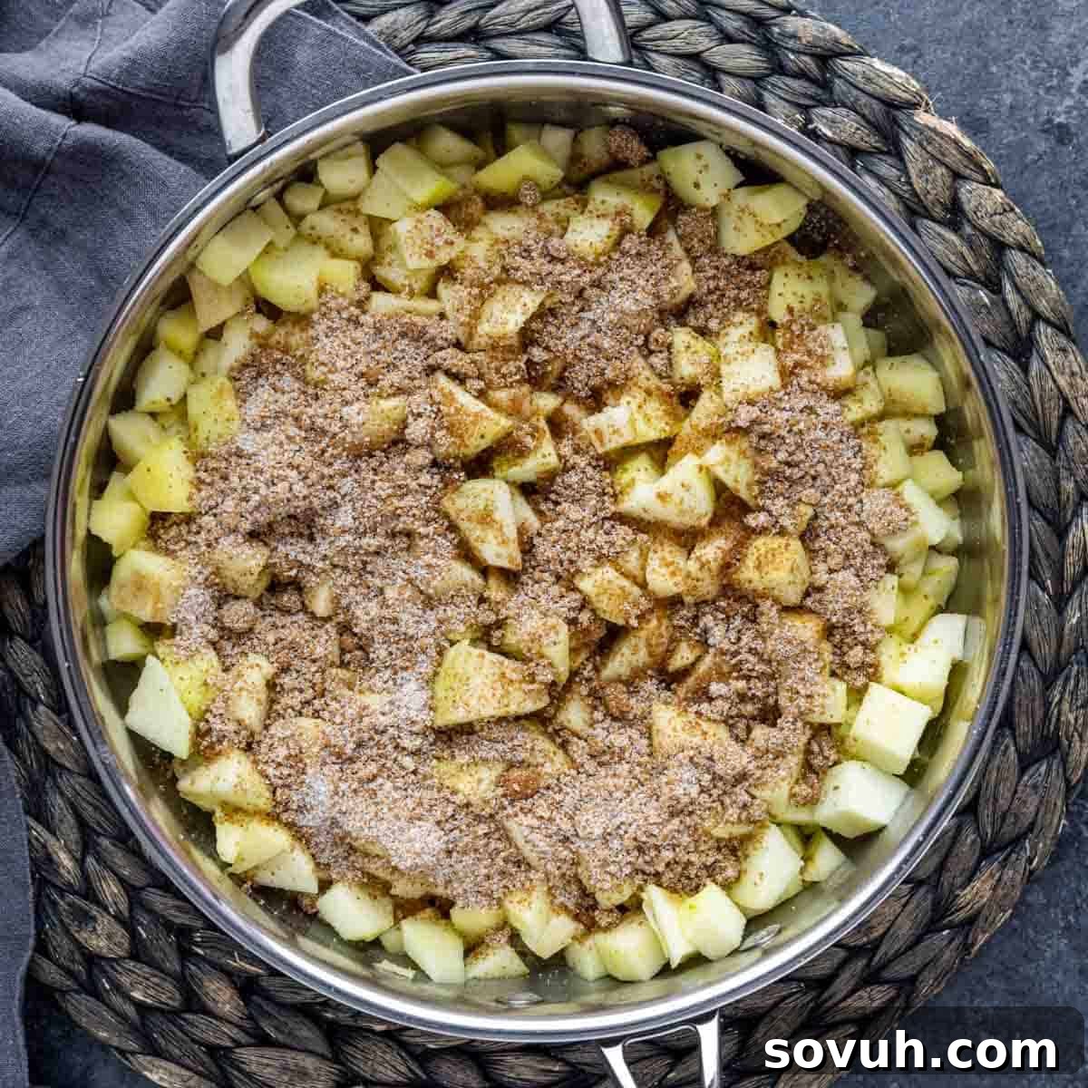 Sliced apples cooking in a pan with cinnamon and sugar for apple pie filling.