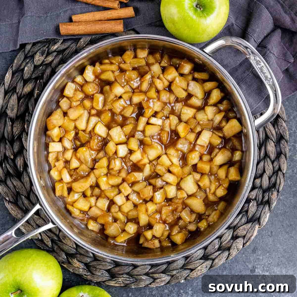 A skillet filled with bubbling homemade apple pie filling on the stovetop.