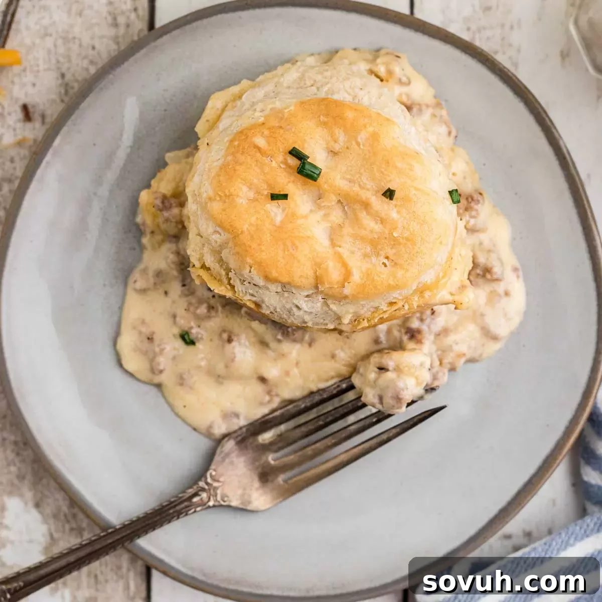A plate with biscuits and gravy casserole on it, garnished with fresh chives.
