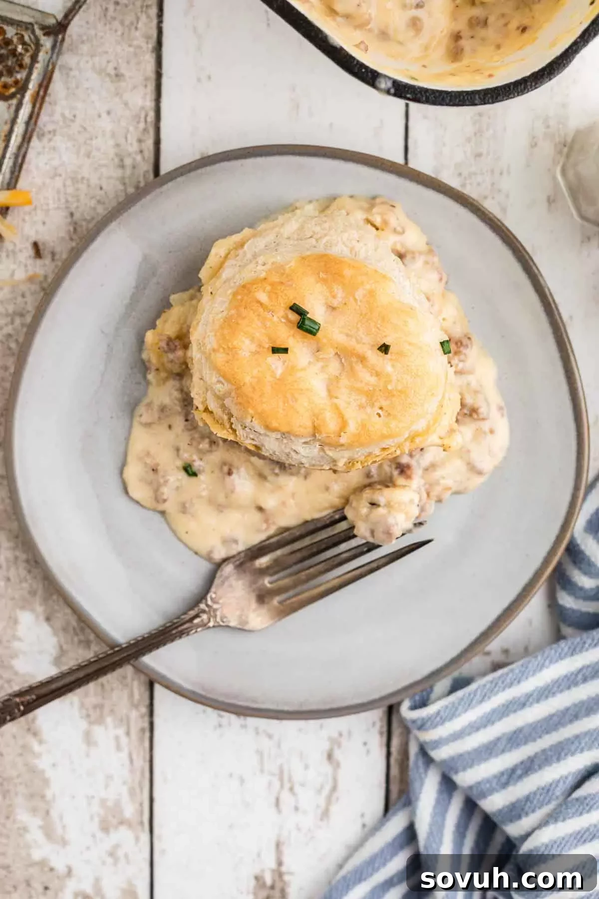 A plate with a generous serving of biscuits and gravy casserole, topped with fresh chives.