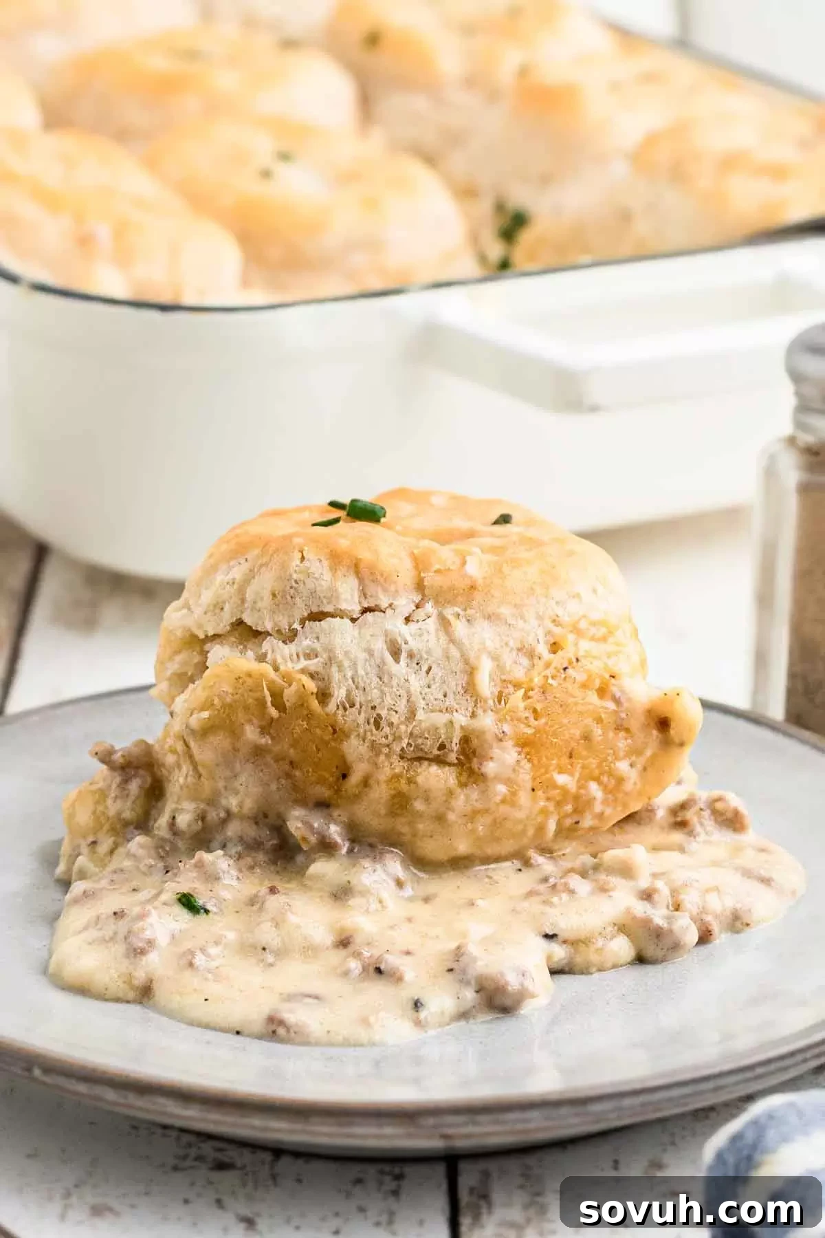 A close-up of a plate with biscuits and gravy casserole, showing the texture of the biscuits and creamy gravy.