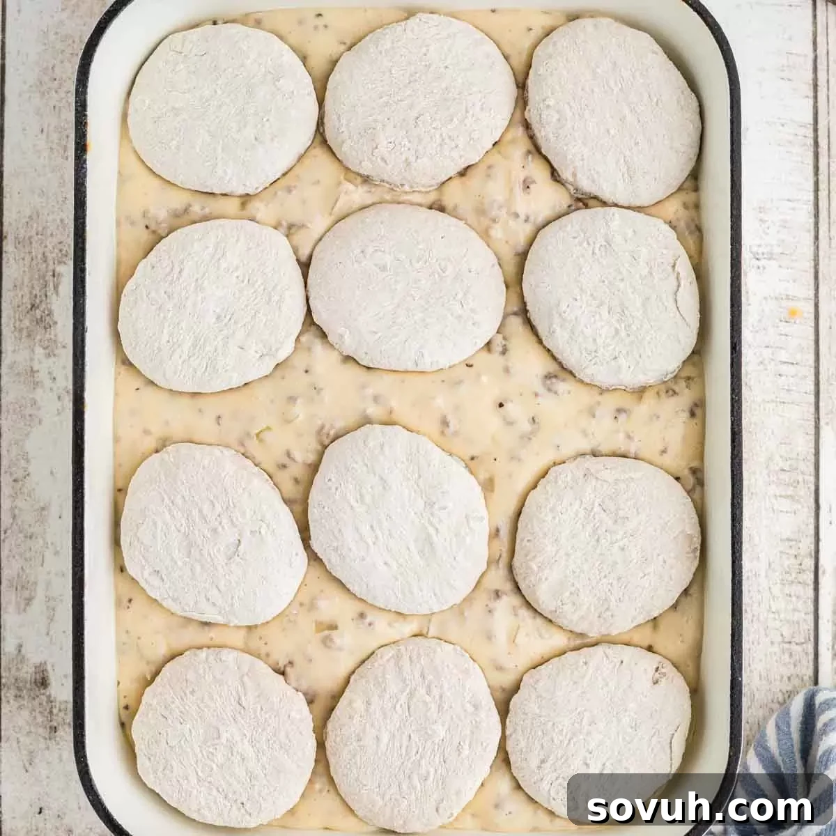 A baking dish filled with a layer of sausage gravy, ready for biscuits.