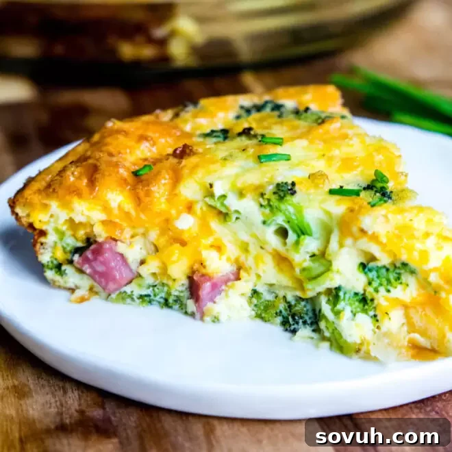 A delectable slice of Low Carb Ham and Cheese Crustless Quiche on a white plate, perfectly cooked and highlighting its rich, flavorful filling of ham and broccoli.