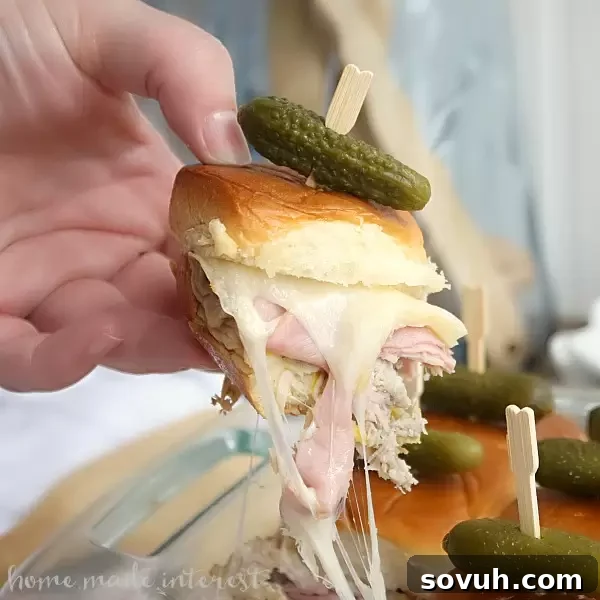 A delectable platter of savory Cuban Sliders, packed with slices of ham, roasted pork, and melted cheese, garnished with mini pickles.