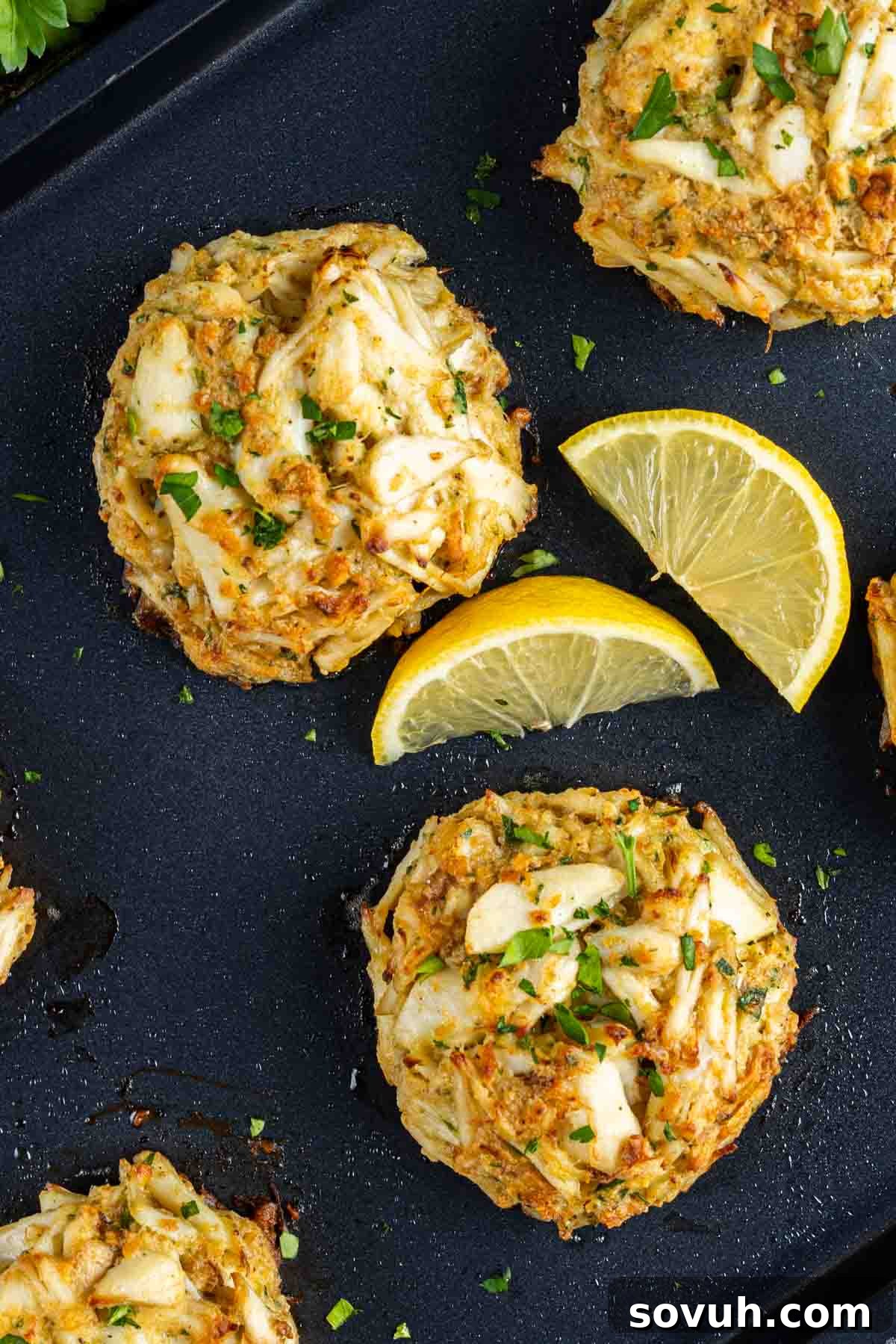 Maryland Crab Cakes on a baking sheet with lemon wedges.