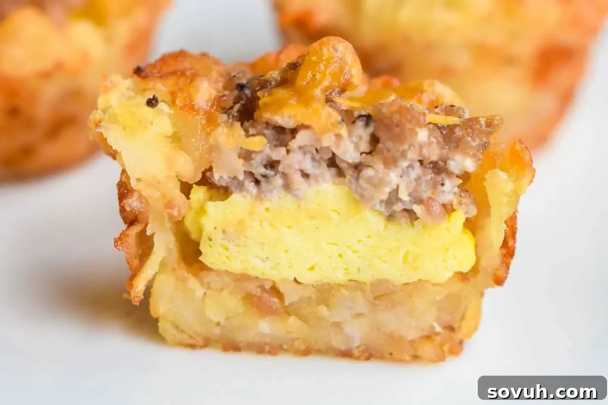 Close-up of a sliced breakfast tater tot showing layers of egg, sausage, and potatoes.