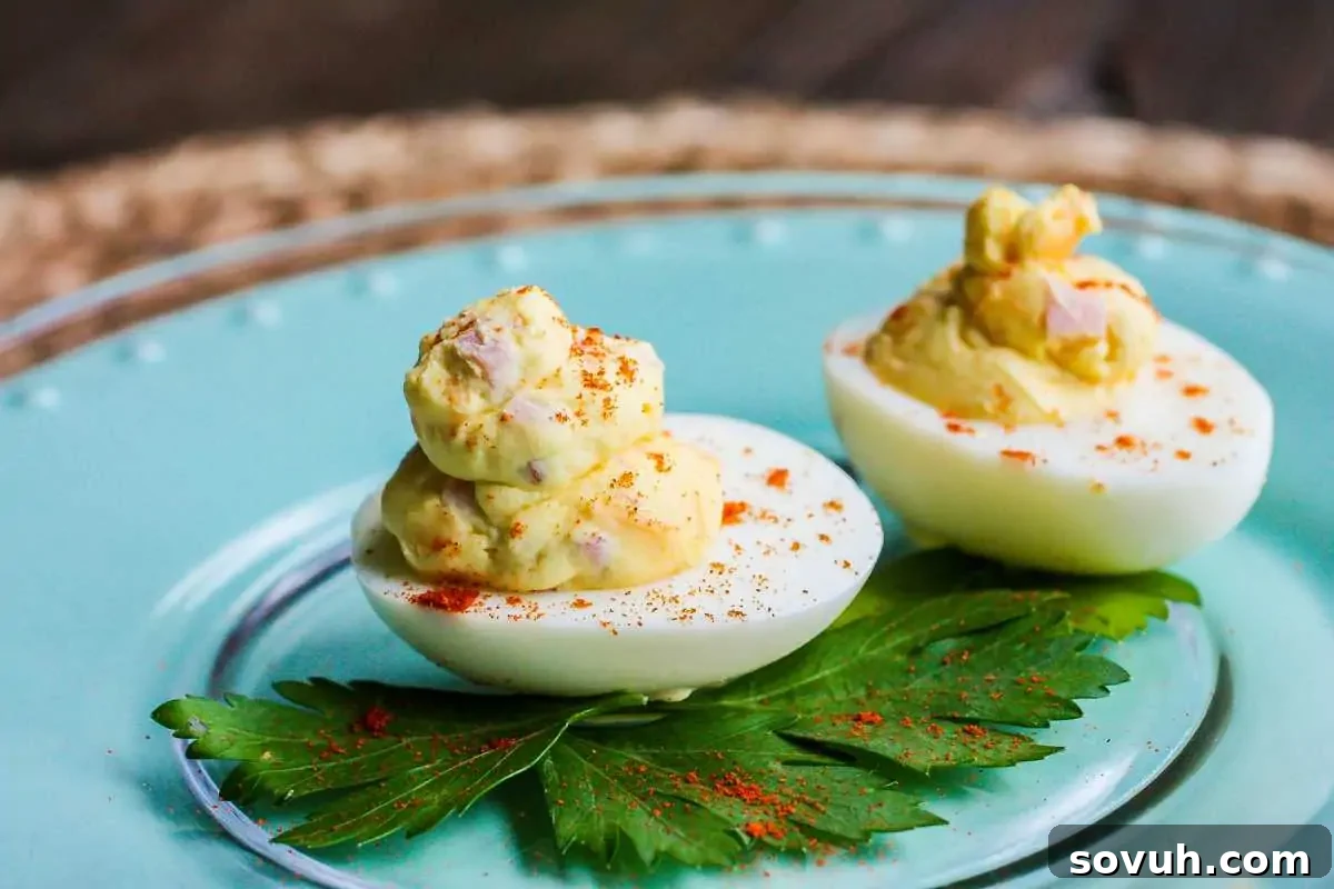 Two deviled eggs garnished with paprika on a blue plate with a green leaf, on a wooden table.