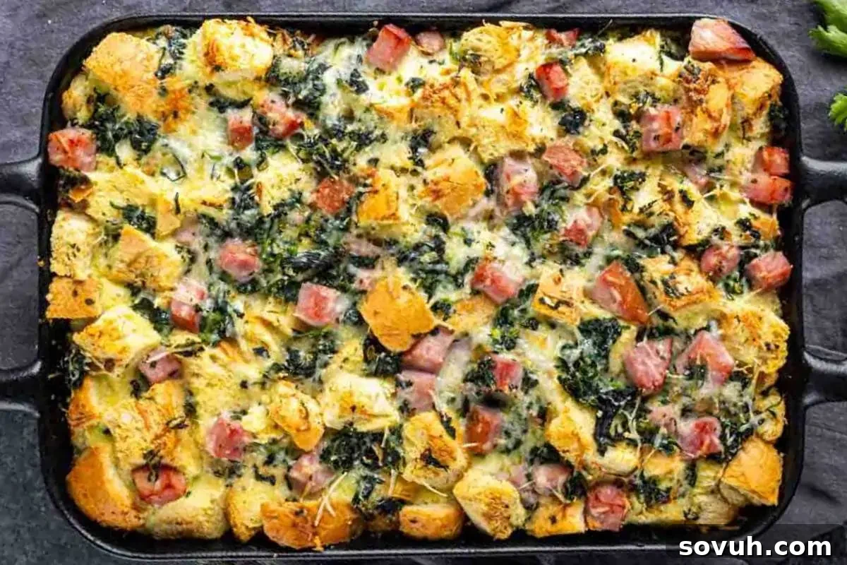Baked egg casserole with spinach, ham, and diced bread in a rectangular dish.