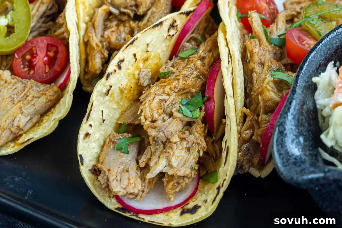 Tender pulled pork tacos garnished with fresh cilantro and pickled red onions.