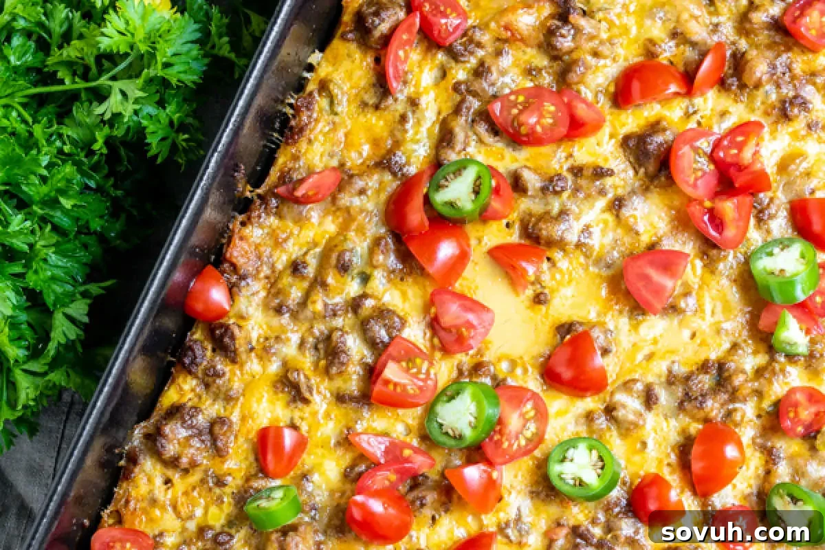 A baked casserole dish showcasing a rich blend of ground beef and melted cheese, beautifully topped with fresh, vibrant tomatoes and fiery jalapeño slices.