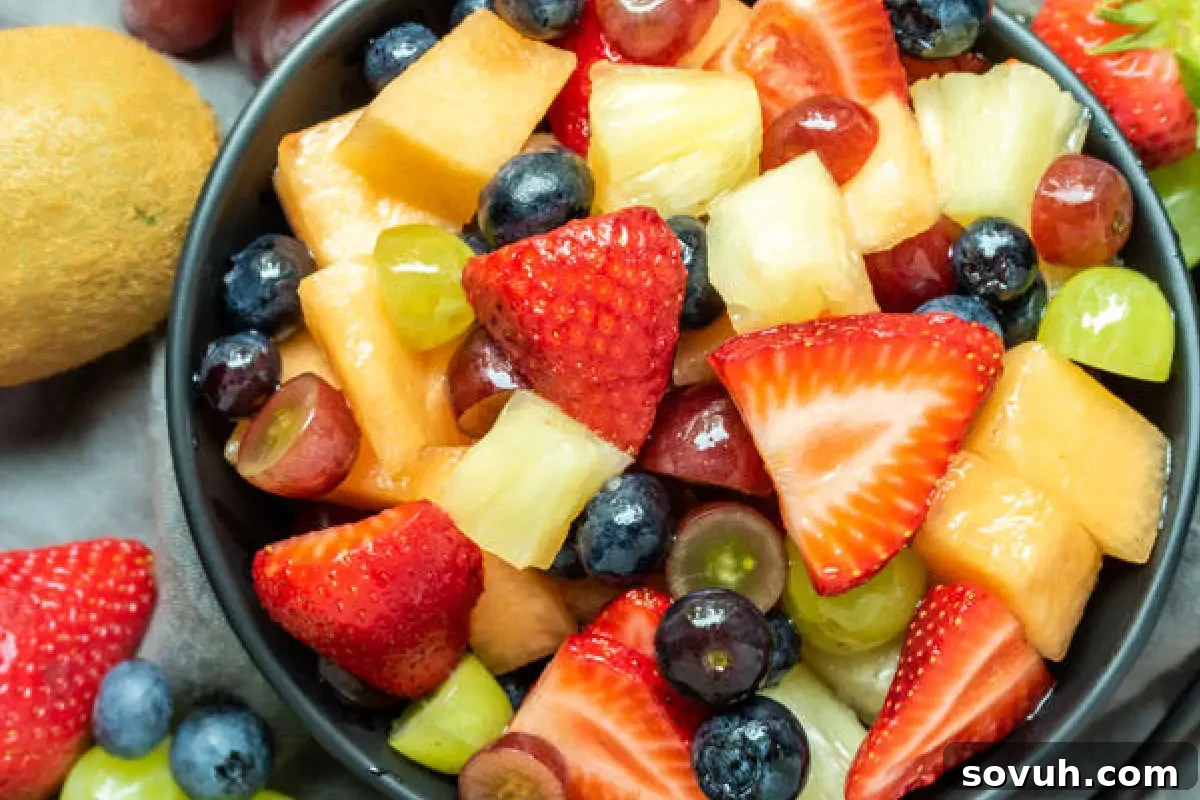 A colorful bowl of mixed fruit salad containing strawberries, blueberries, grapes, and diced melon.