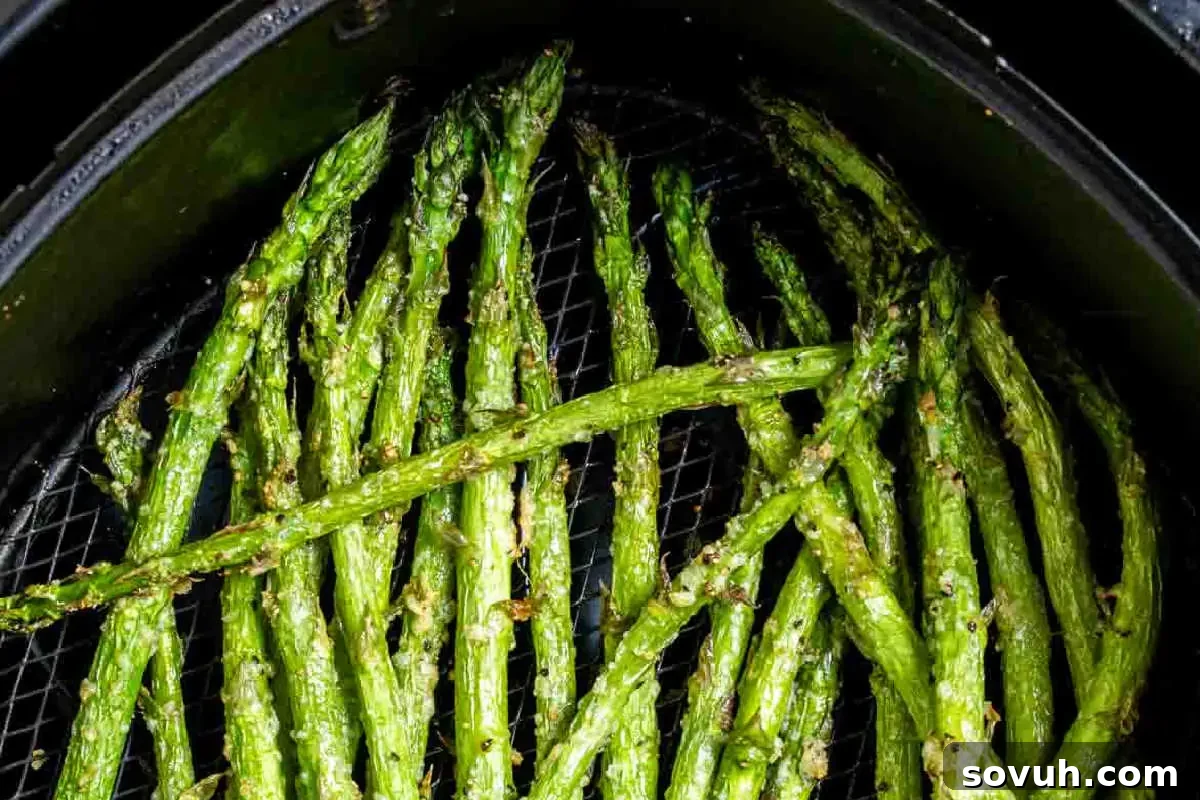Roasted asparagus spears in an air fryer basket.