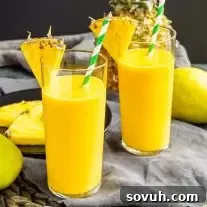 two Mango Pineapple Smoothie with pineapple wedges