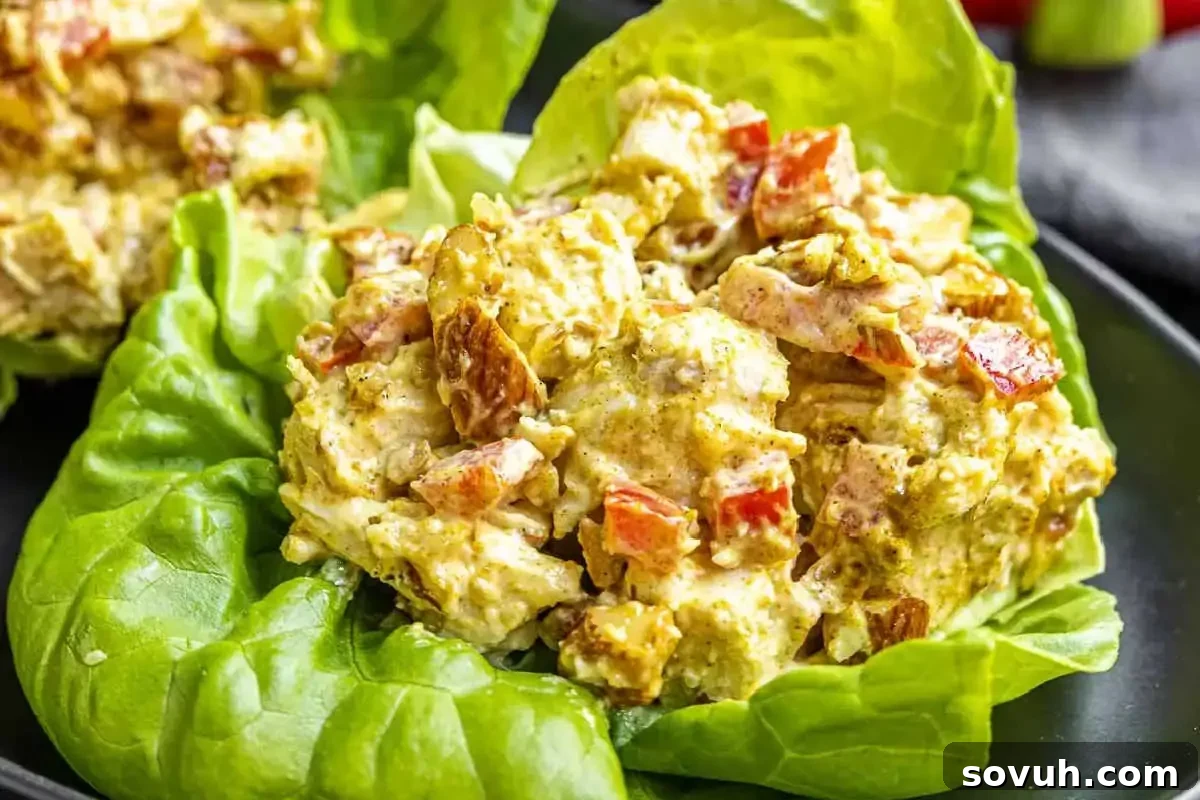 Chicken salad with diced tomatoes served in lettuce cups on a black plate.