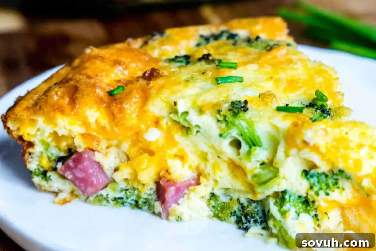 A slice of broccoli and ham quiche garnished with chives on a white plate.