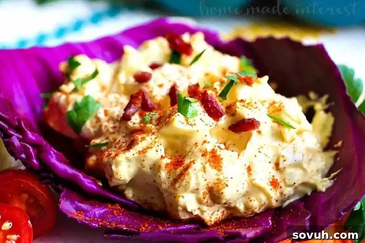 A vibrant image showcasing a purple cabbage leaf bowl filled with creamy egg salad, topped with bacon bits and paprika, garnished with parsley.