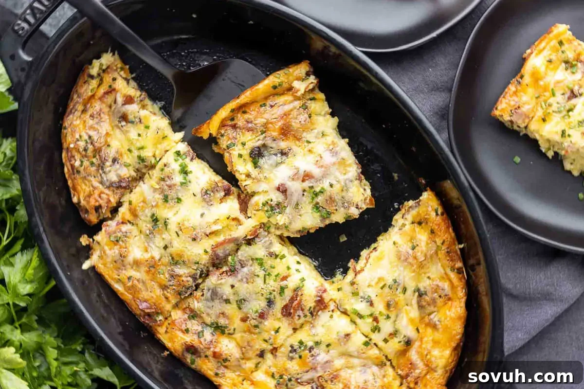 A frittata with bacon and herbs, partially sliced in a skillet with one piece on a black plate.