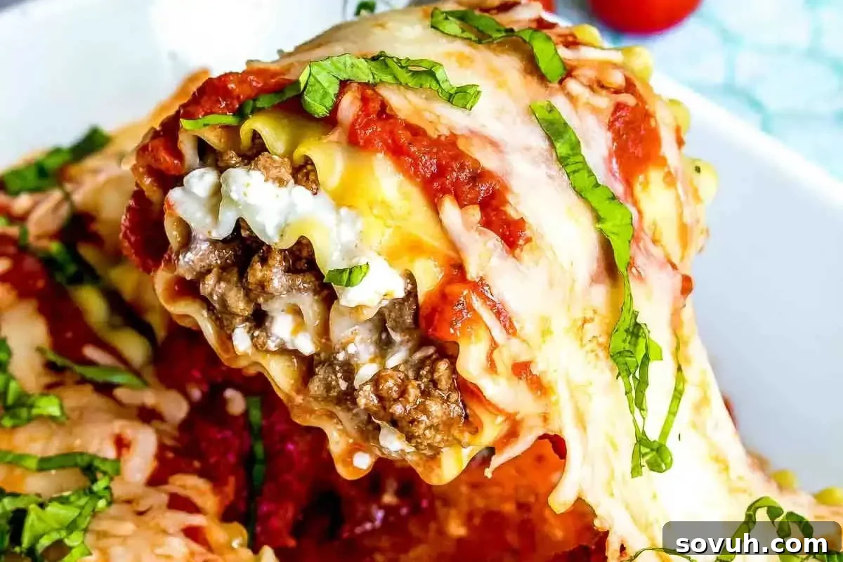Delicious Lasagna Roll Up being served, revealing rich layers of seasoned ground beef, creamy ricotta, marinara sauce, and melted mozzarella, garnished with fresh basil. Perfect for a family dinner or meal prep.