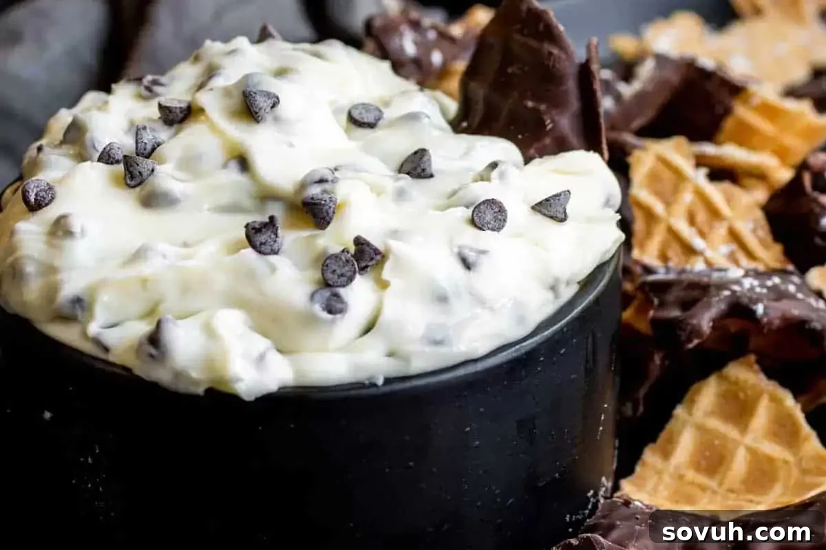A bowl of creamy, sweet dip topped with mini chocolate chips, surrounded by broken cannoli shells for dipping.
