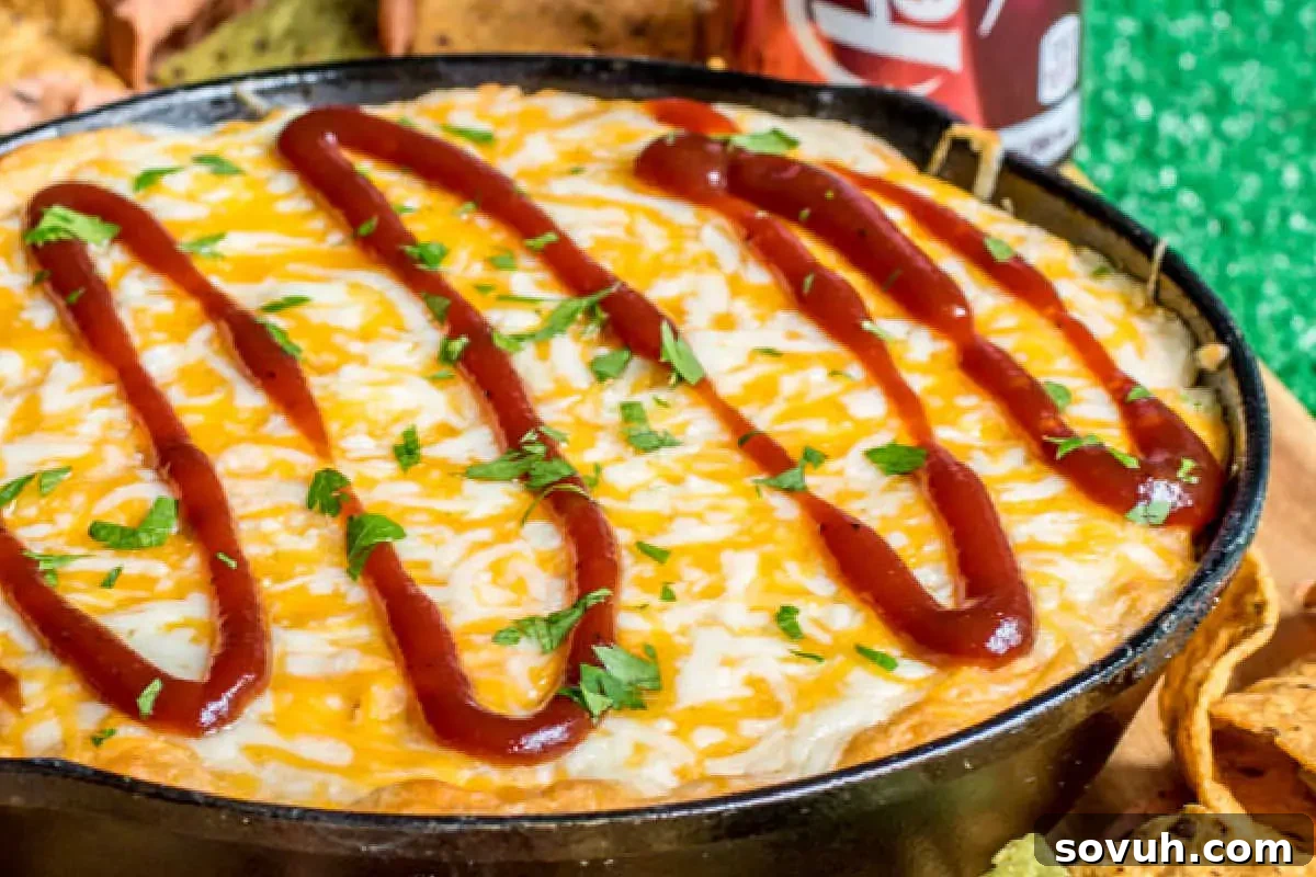 A skillet of creamy, melted cheese topped with zigzagging lines of red sauce, garnished with chopped herbs, surrounded by crispy tortilla chips.
