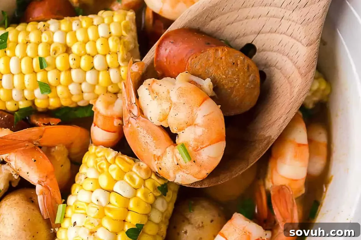 A wooden spoon holds shrimp, sausage, and corn, surrounded by more shrimp, corn on the cob, and potatoes in a dish.
