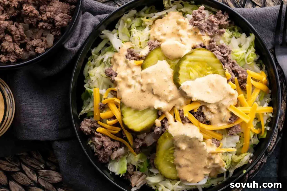 A bowl of salad with shredded lettuce, ground beef, sliced cucumbers, shredded cheese, and creamy dressing, mimicking Big Mac flavors.