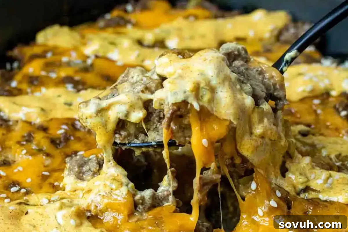 A close-up image of cheesy beef nachos with a fork lifting a portion, showing melted cheese stretching.