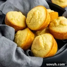 A black bowl filled with freshly baked Southern Cornbread muffins, lined with a gray cloth napkin.