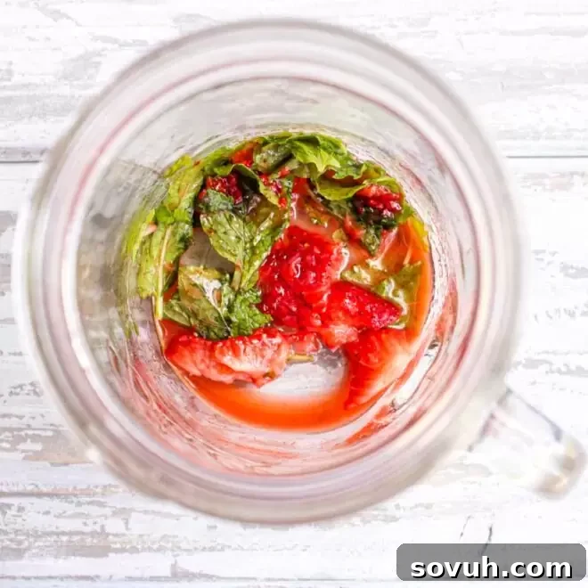 Strawberries and mint muddled in a glass jar.