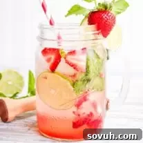 Strawberry mojito mocktail in a mason jar with limes and strawberries.