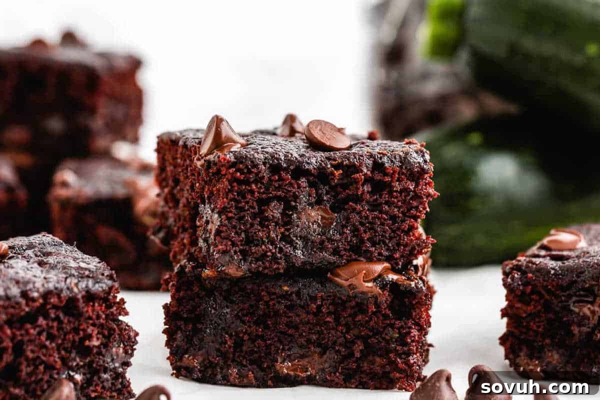 A stack of two chocolate brownies with chocolate chips on top, placed on a white surface.