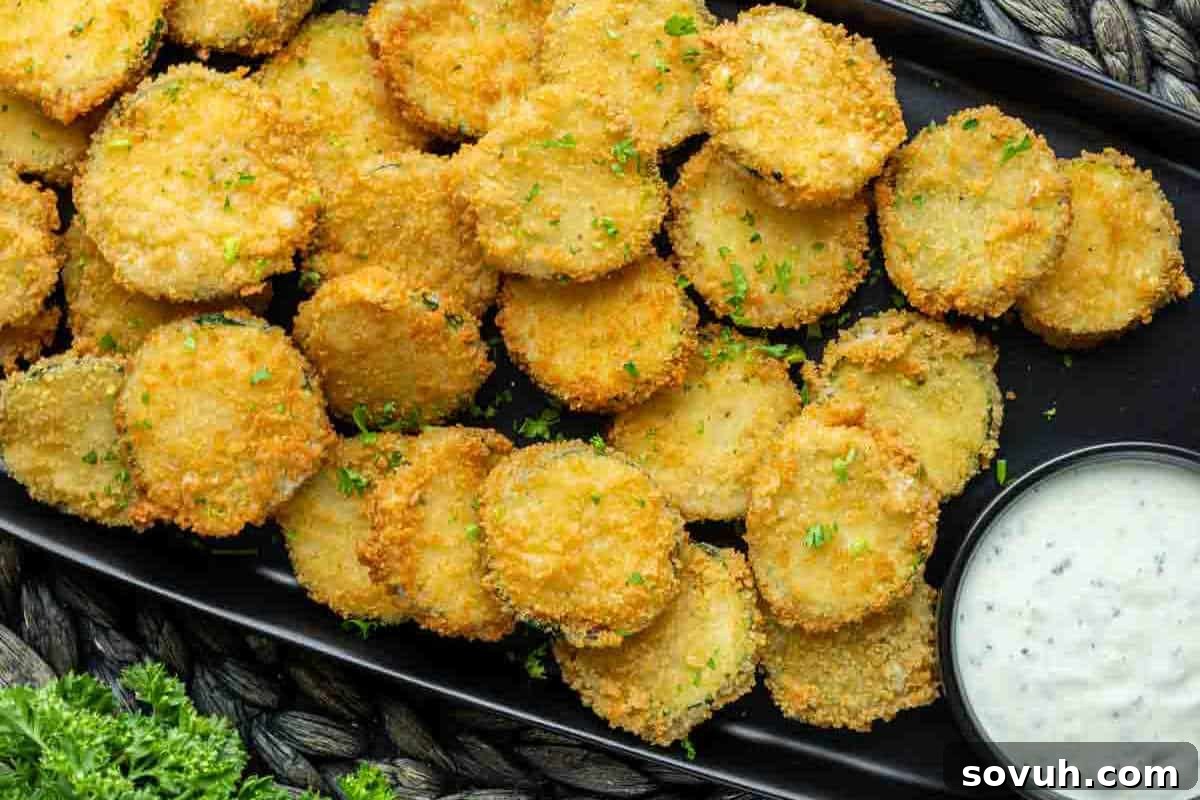 A plate of breaded and fried pickle slices garnished with parsley, accompanied by a small cup of dipping sauce.