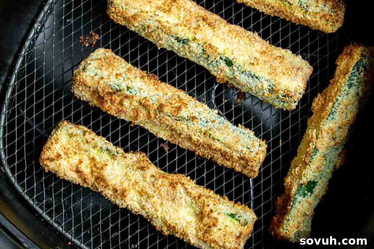Breaded zucchini sticks on a wire mesh rack, baked until golden brown.