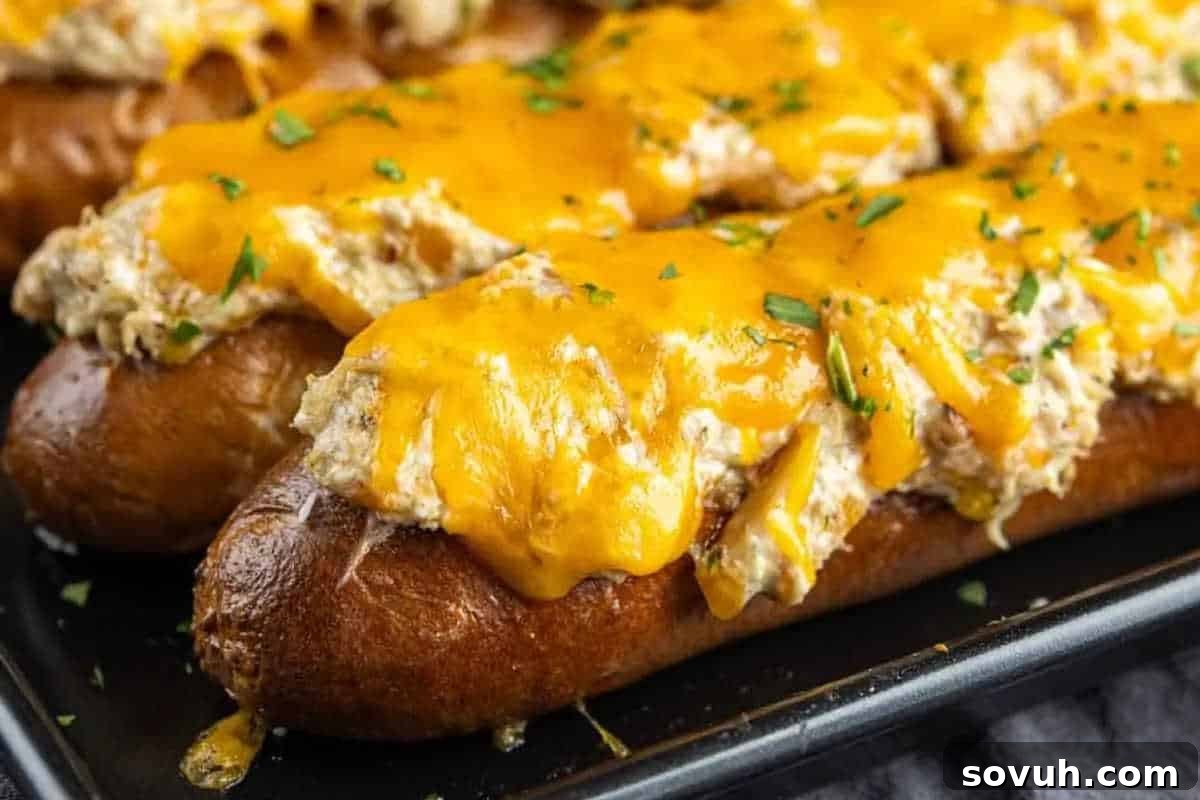 A unique appetizer featuring hot pretzel dough generously topped with a rich, melted cheddar cheese and a creamy crab mixture, elegantly garnished with finely chopped fresh herbs, presented on a baking tray.