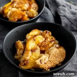 A black bowl filled with Peach Cobbler Using Canned Peaches, featuring baked peaches and a golden-brown crust.