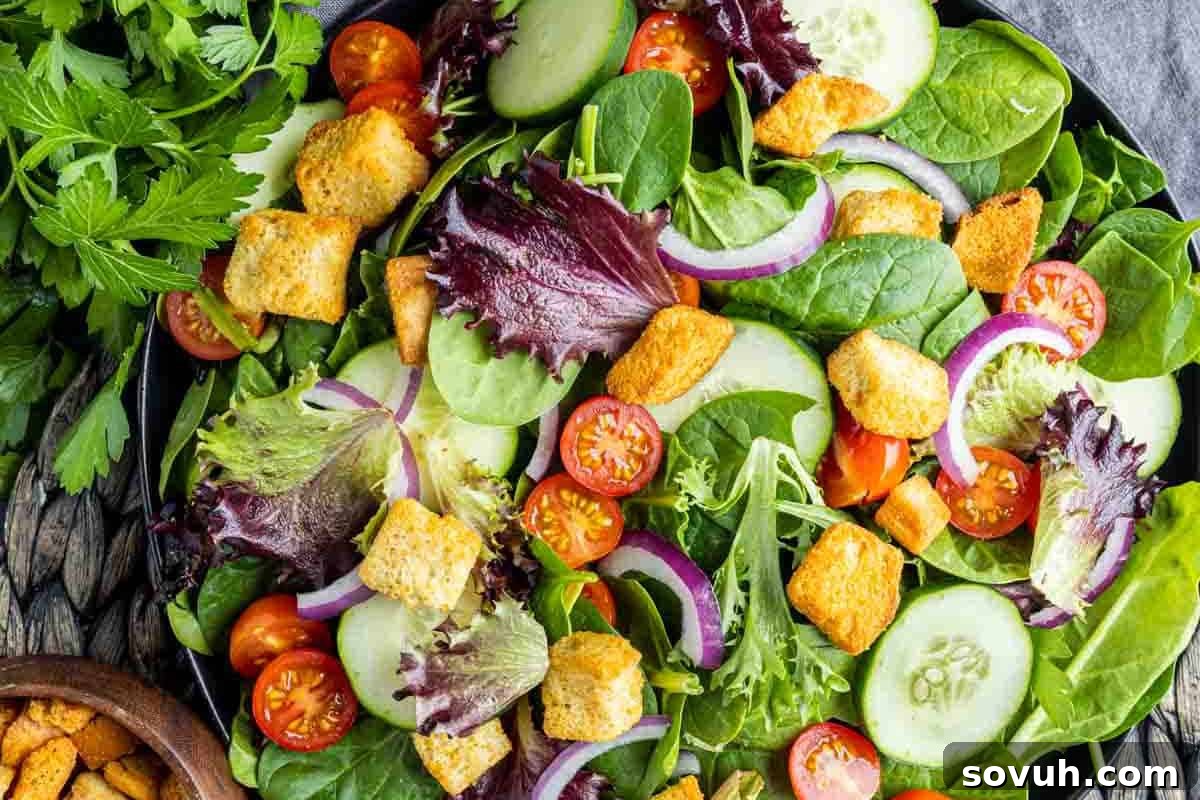A fresh salad with mixed greens, cherry tomatoes, cucumber slices, red onion, and croutons, garnished with a side of parsley.