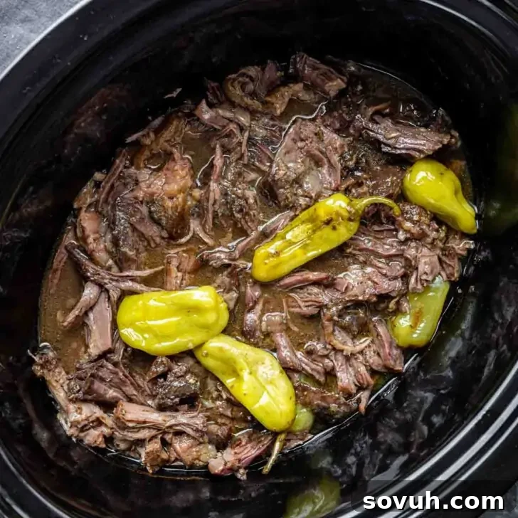 Mississippi Pot Roast: Slow Cooked Southern Charm 2 A perfectly cooked Slow Cooker Mississippi Pot Roast, rich brown broth, and vibrant yellow pepperoncini peppers in a slow cooker.