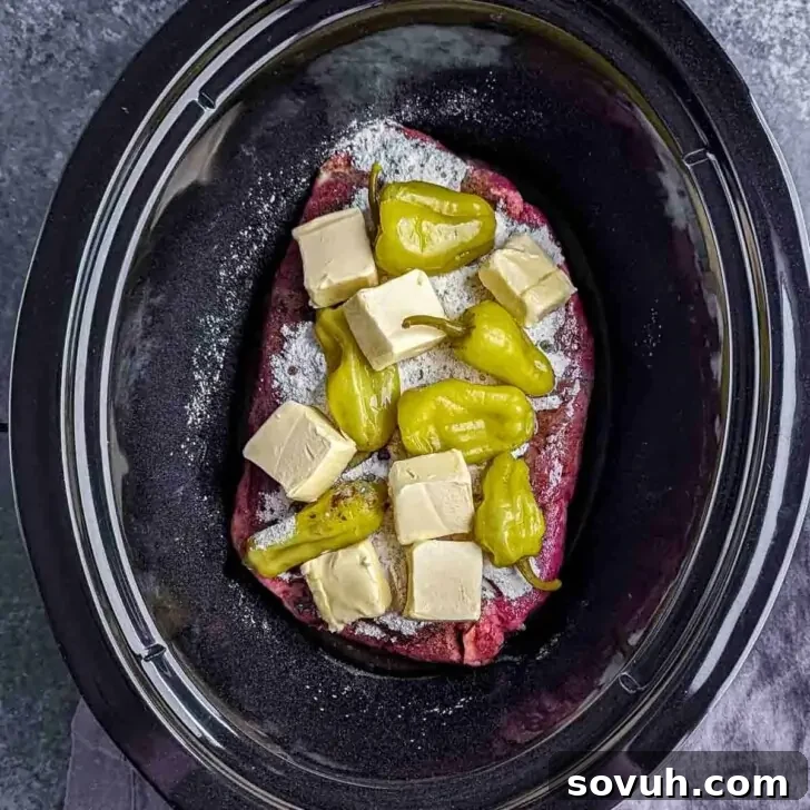 Mississippi Pot Roast: Slow Cooked Southern Charm 3 Raw chuck roast, butter cubes, and pepperoncini peppers in a slow cooker, ready to be seasoned for Mississippi Pot Roast.