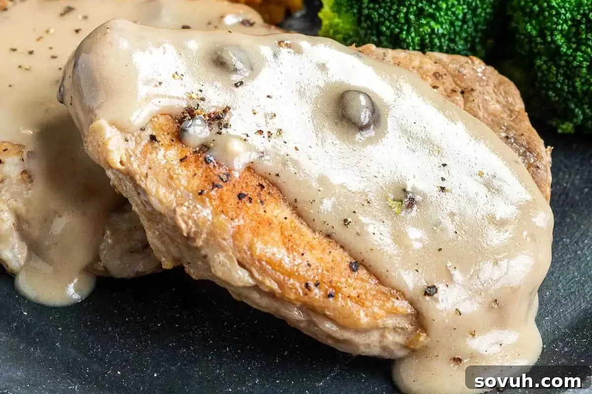Close-up of seared pork chops topped with creamy mushroom sauce, accompanied by bright green steamed broccoli florets.