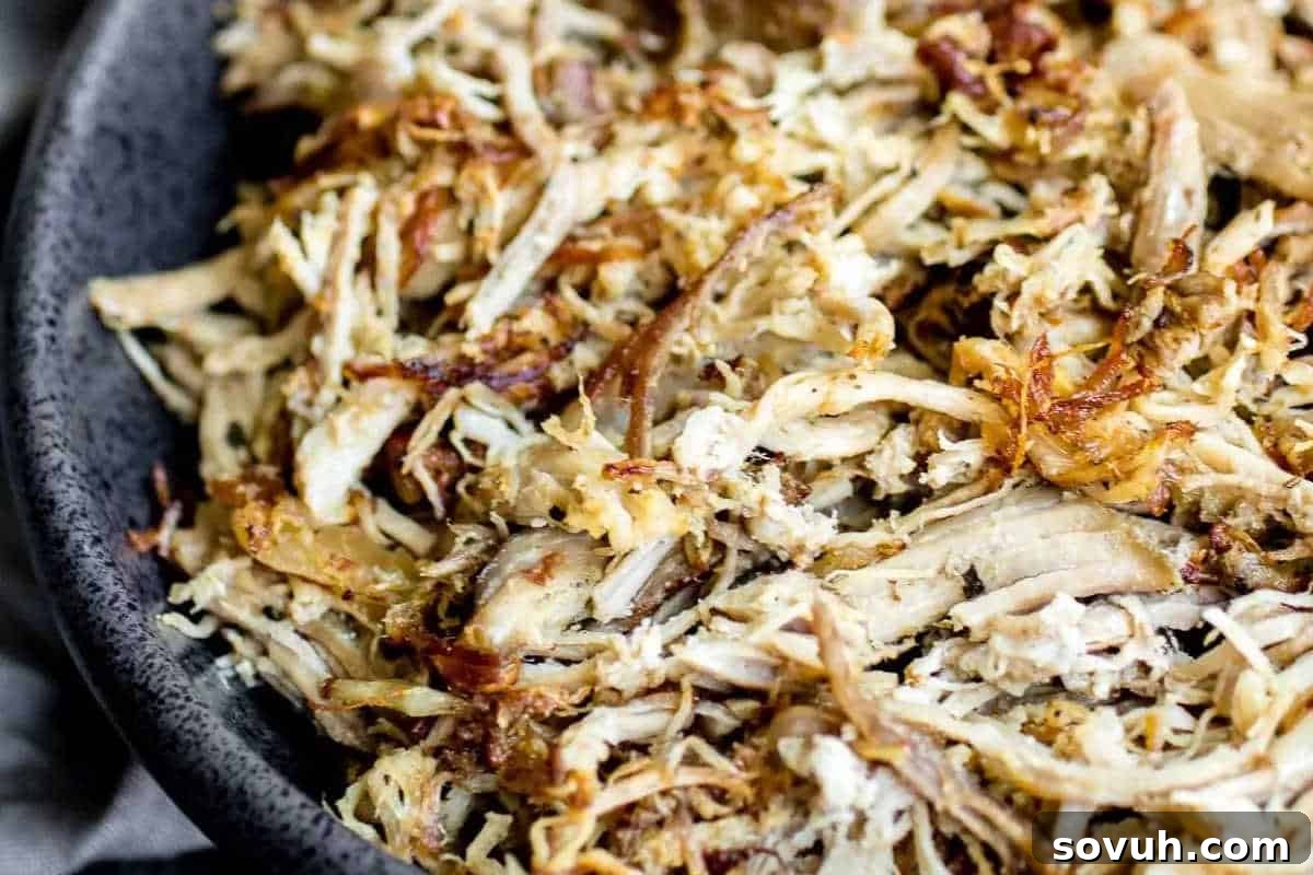 A close-up view of shredded, cooked meat with slightly crispy edges in a dark-colored bowl.