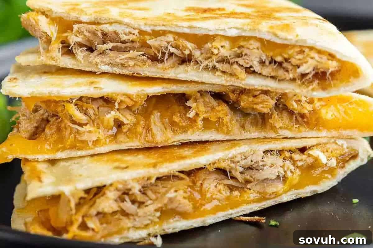 A stack of three quesadilla wedges filled with shredded chicken and melted cheese.