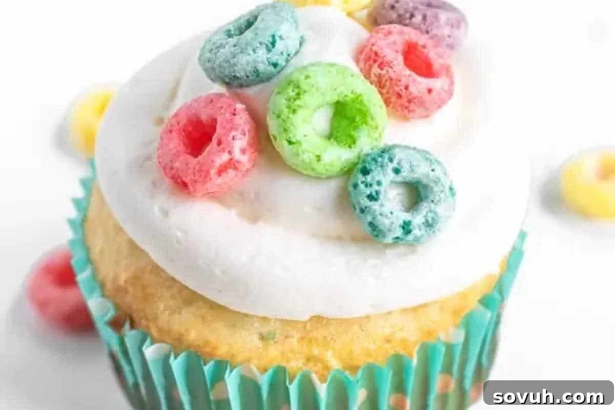 Cake Mix Magic 14 A vanilla cupcake with white frosting, topped with colorful cereal loops, in a turquoise paper liner.
