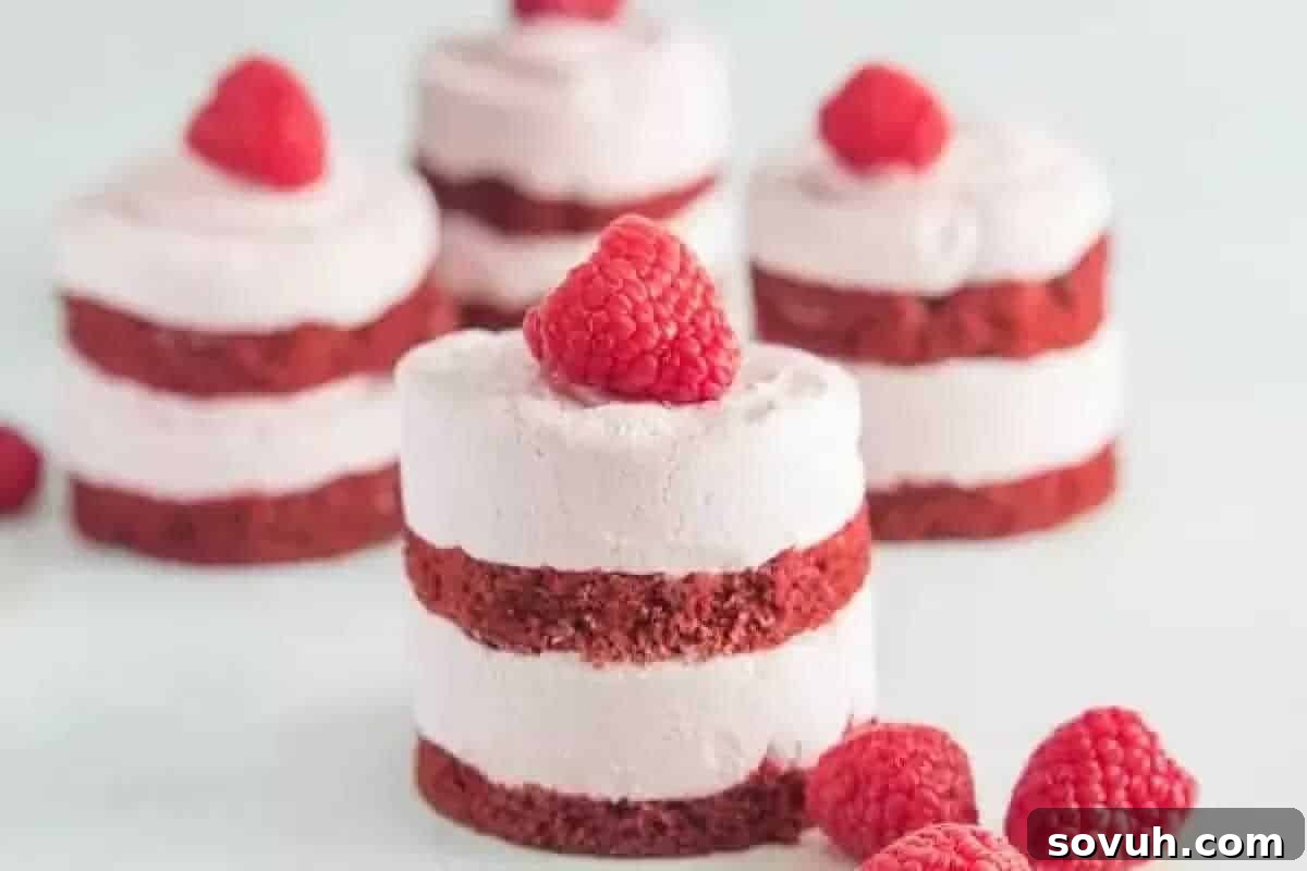 Cake Mix Magic 3 Miniature red velvet cakes made from premium cake mix with layers of frosting, each topped with a fresh raspberry. Sweet cheats include additional raspberries scattered around the desserts.