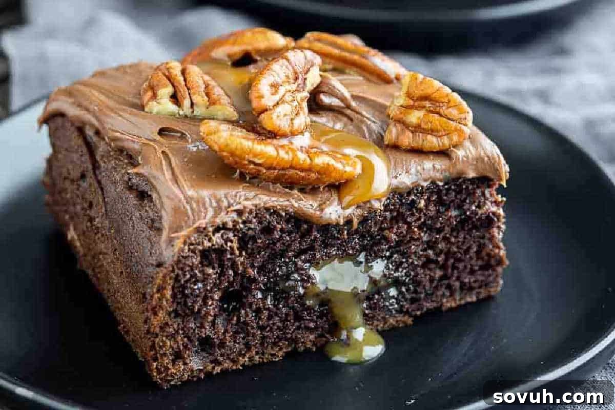 Cake Mix Magic 4 A slice of chocolate cake with caramel oozing from the center, topped with chocolate frosting and pecans, served on a black plate.