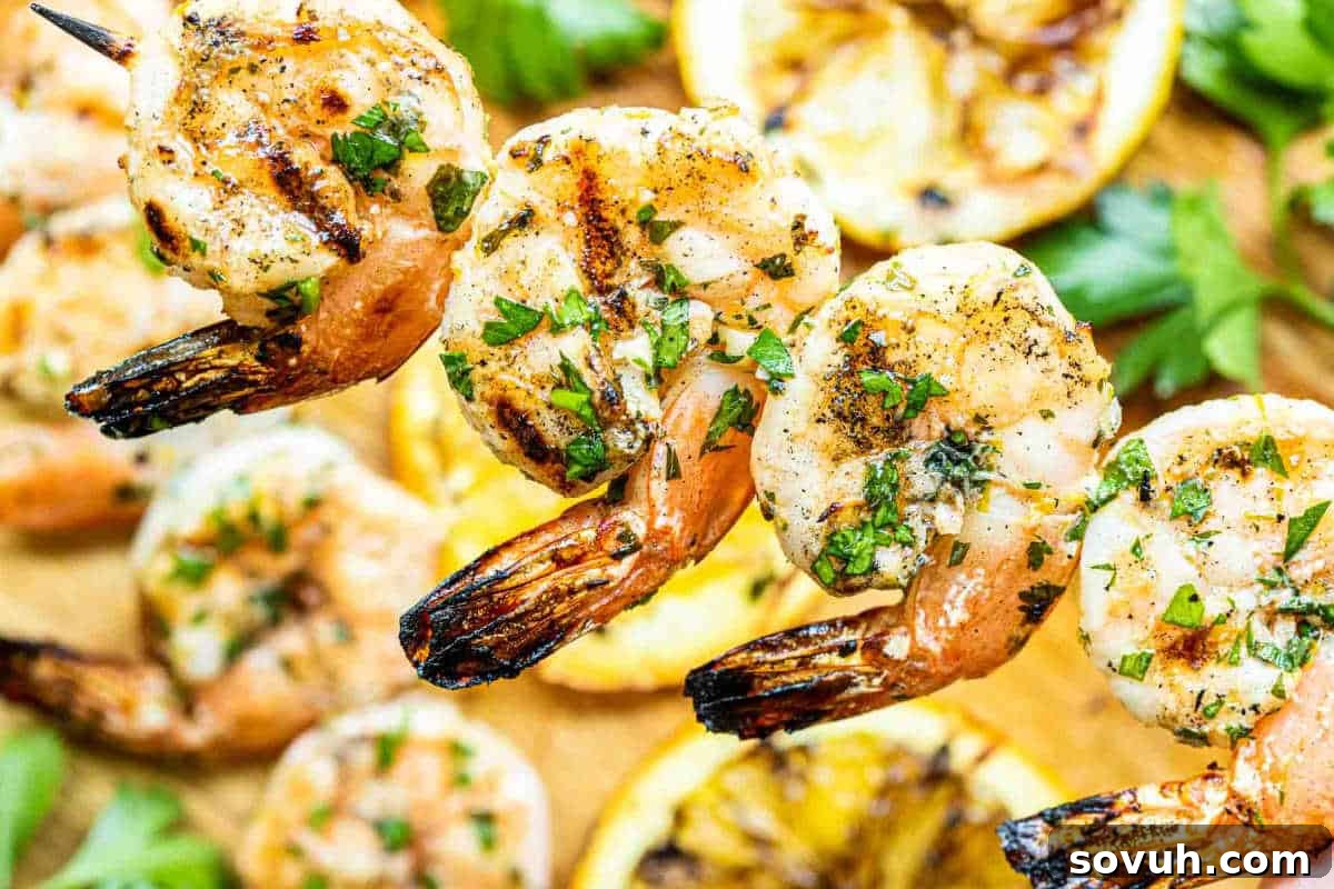 Close-up image of grilled shrimp skewers garnished with herbs, accompanied by grilled lemon slices and fresh greens.