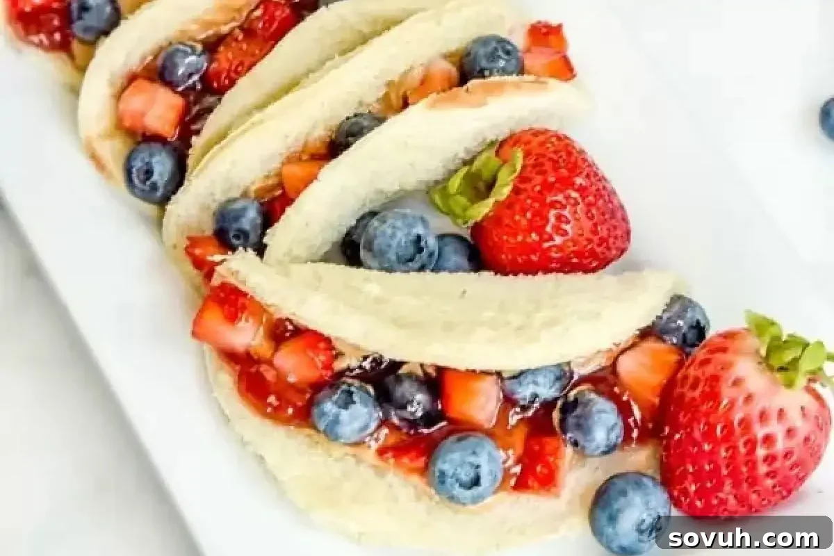 Four slices of sandwich bread filled with chopped strawberries, blueberries, and jam, garnished with whole strawberries and blueberries on the side, plated on a white dish.