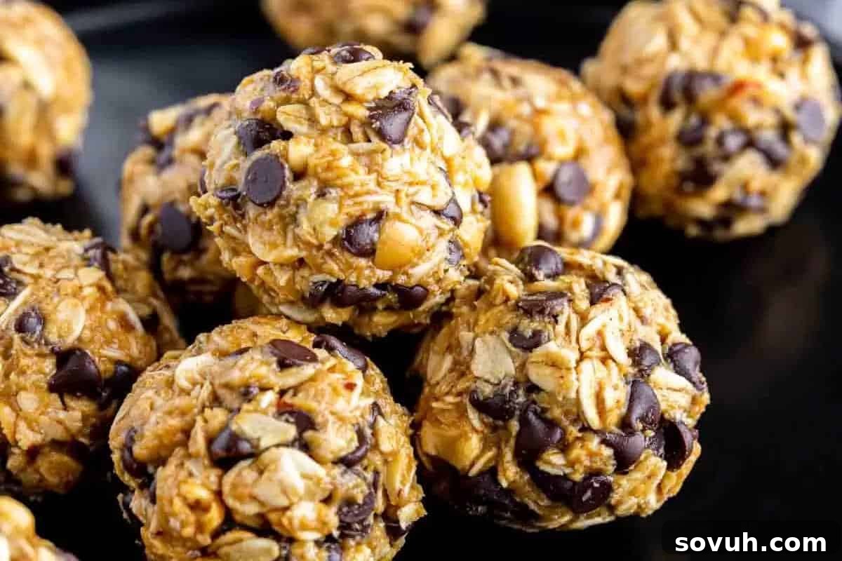 A close-up of energy bites made from rolled oats, chocolate chips, and nuts arranged on a black surface.