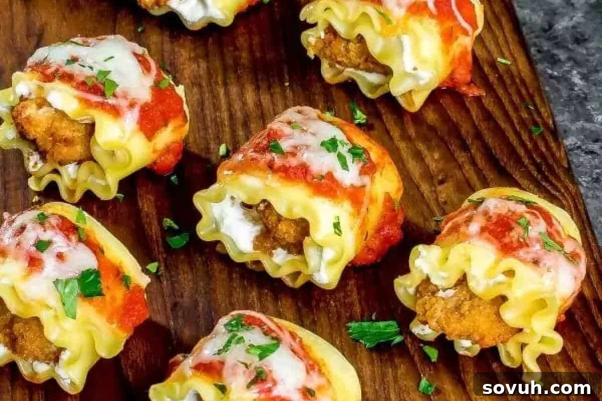 Mini lasagna rolls with a crispy filling, topped with marinara sauce, melted mozzarella, and sprinkled with fresh parsley on a wooden board.